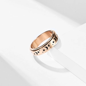 Detail of rose gold spinner ring with engraved moon and stars on a white background
