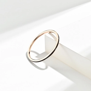 Bague empilable 1mm en or rose avec émail noir posée sur un bloc géométrique blanc