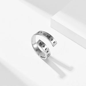 Macro detail of polished stainless steel open ring with Nordic rune symbol engravings