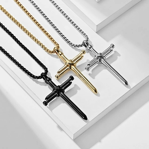Dettaglio di tre collane a croce in acciaio inossidabile nei colori nero, oro e argento
