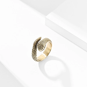Close-up of vintage gold snake ring with detailed scale texture on white platform