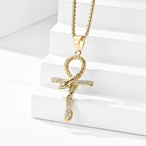 Detail eines goldenen Ankh-Kreuzanhängers mit Schlangendesign und weißen Kristallen