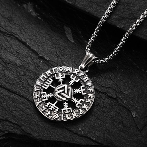 Dettaglio macro dei simboli Valknut e Vegvisir incisi sul ciondolo vichingo in acciaio