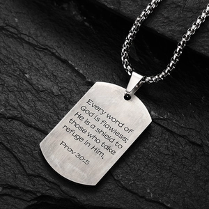 Polished stainless steel cross dog tag necklace with engraved scripture on a stone base