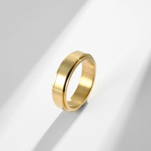 Polished gold spinner ring with brushed texture on a modern geometric light background