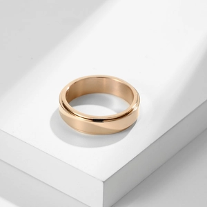 Polished rose gold stainless steel spinner ring displayed on a minimalist white stand