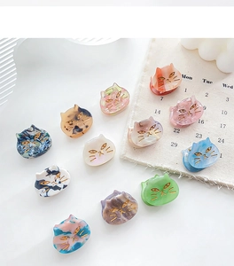 Flat lay of diverse acetate cat-shaped hair claws with golden engraved face details