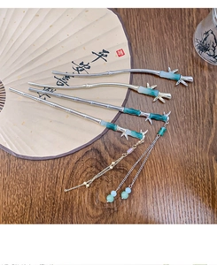 Detailed macro view of silver bamboo style hairpins with green faux jade on a wooden table