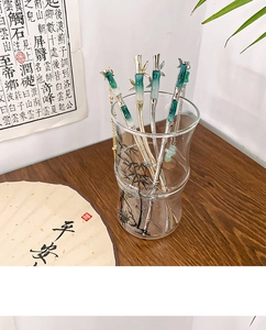 Detailed view of four bamboo-shaped silver hairpins with green faux jade and tassels