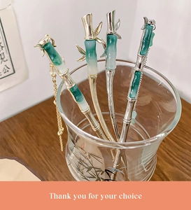 Detail of silver bamboo-shaped hairpins with green jade-like accents and golden tassels