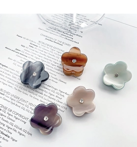Détail de cinq mini pinces à cheveux fleurs colorées avec strass sur fond blanc poli