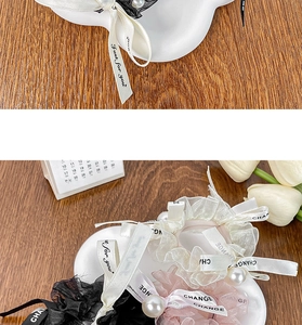 Close-up of elegant cream organza scrunchies with pearls and long ribbons on wood