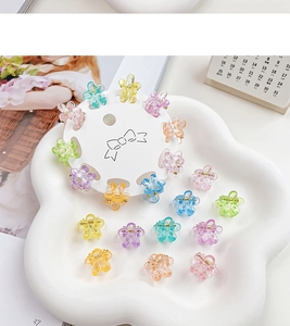 Detail view of mini flower hair claws with glitter in colorful jelly shades on a tray