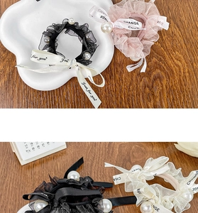 Close-up of chiffon lace hair scrunchies with text ribbons and large pearl accents