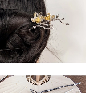 Detail of silver plum blossom branch hair stick with gold stamens and hair styling