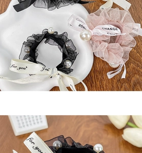 Detail of lace bow hair scrunchie with pearls and printed ribbons in cream and black