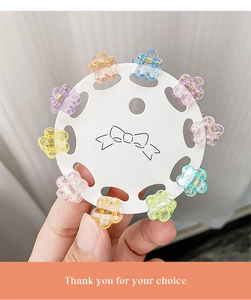 Macro detail of 10-piece glitter flower mini hair claws set on white display card