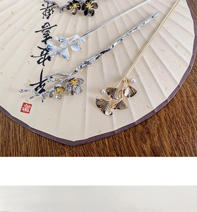 Close-up of vintage metal flower hairpins with pearls on a traditional paper fan background