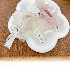 Detail of cream and pink organza hair scrunchies with pearls on a cloud tray