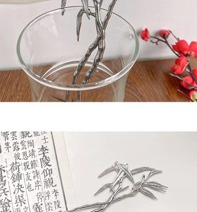 Detail of silver bamboo-style hairpins on calligraphy paper showing metallic luster