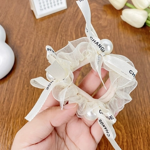 Elegant cream lace scrunchie with pearls and printed ribbon bow on wooden background