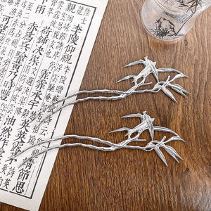 Chinese style silver metal hairpins with bamboo leaf and bird design on dark wood