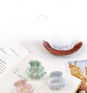 Detailed close-up of acetate hair claws in pastel stripes on a classic book page