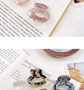 Close-up of premium acetate claw clips in marble and tortoiseshell finishes on a book