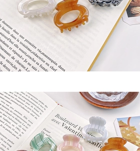 Detailed view of colorful acetate hair claws on a book for high ponytail styling