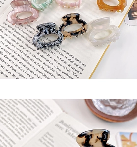 Close-up of elegant acetate hair claws in various patterns on a vintage book