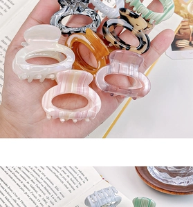 Close-up of colorful acetate hair claws in marble and tortoiseshell patterns on an open book