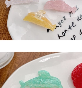 Detail of candy-colored dolphin hair clips with glitter texture on ceramic tray