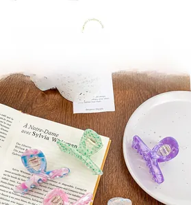 Détail de diverses pinces à cheveux colorées en acétate sur un bureau en bois avec plat