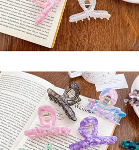 Détail de pinces à cheveux en acétate marbré de diverses couleurs sur un livre ouvert