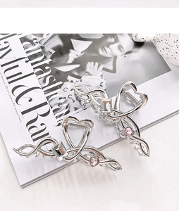 Macro view of silver metal hair claw with wave lines and pink heart crystal detail