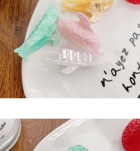 Detailed view of dolphin hair clips in glittery mint, pink, white, and yellow colors