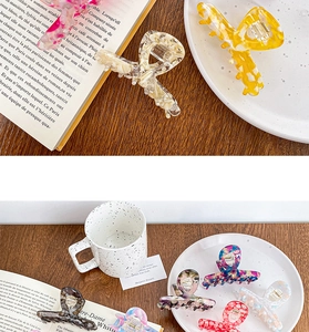 Diverses pinces à cheveux en acétate aux motifs marbrés et floraux sur une table bois