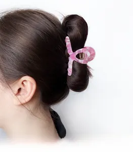 Vue détaillée de la pince à cheveux en acétate marbré rose sur un chignon bas