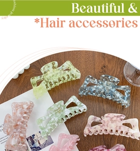 Détail de grandes pinces à cheveux en acétate marbré aux tons vert menthe et pêche