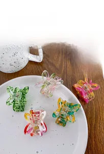 Set of five hollow acetate butterfly hair claws with colorful marble textures on a ceramic plate