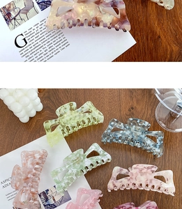 Vue détaillée de grandes pinces à cheveux en acétate aux motifs marbrés colorés sur bois