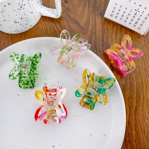 Five butterfly acetate hair claws with marble textures in a lifestyle setting