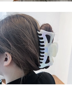 Gros plan d'une grande pince à cheveux en acétate marbré blanc portée en chignon