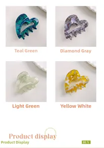 Detail of heart-shaped acetate hair claws in green marble, gray, and yellow patterns