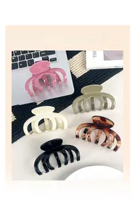 Close-up of assorted large claw clips in trendy colors placed on a laptop and book