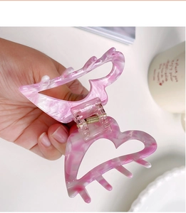 Detail of pink marble heart hair claw clip showing acetate texture and metal spring