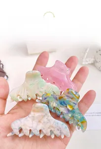Detail view of four colorful acetate hair claws in pastel marble and floral patterns