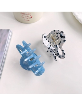 Close-up of heart-shaped acetate hair claws in blue and black star pattern on a white desk