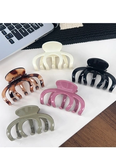 Detailed view of large hair claw clips in five stylish colors on a minimalist desk