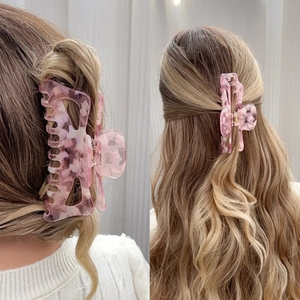 Grande pince à cheveux en acétate marbré rose pour cheveux épais sur fond gris clair discret